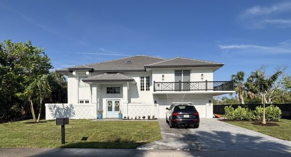 street view of white painted stucco home with driveway and front yard