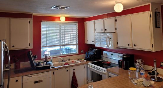 Interior kitchen painting with red walls and white cabinets