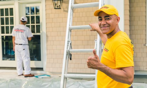 Exterior house painters with tarps, brushes and ladders.