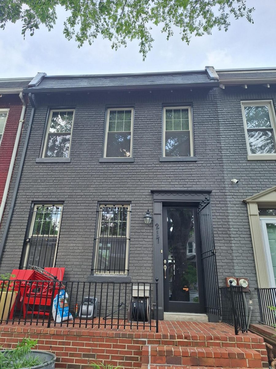 front exterior of grey painted brick townhouse with black door and trim