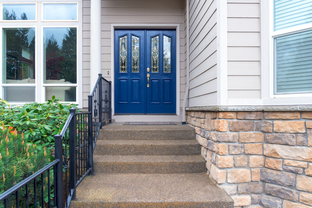 House steps with black railing, leading up to a pair of dark blue double doors