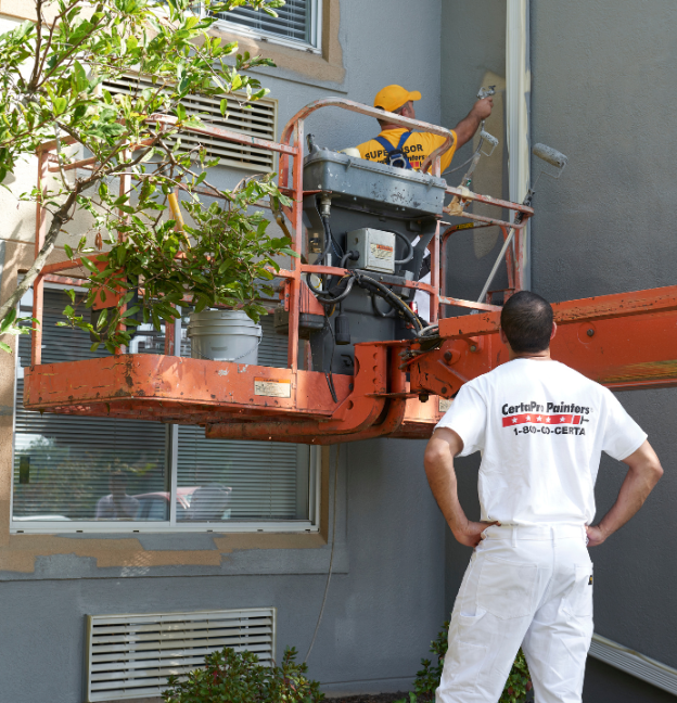 certapro painter watching crew member paint apartment exterior on lift