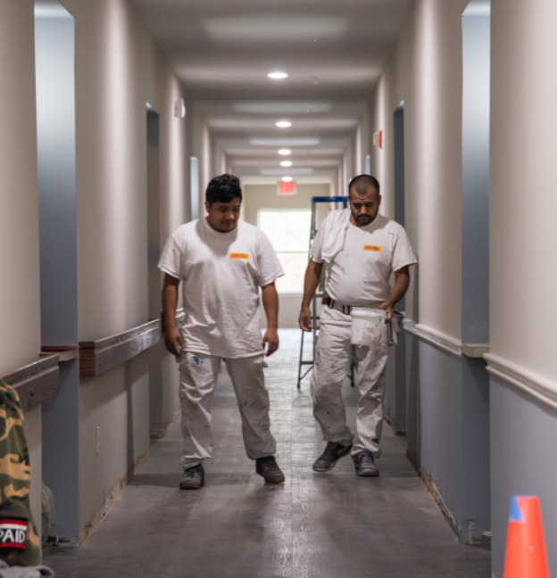 two certapro painters crew members painting hallway in commercial space