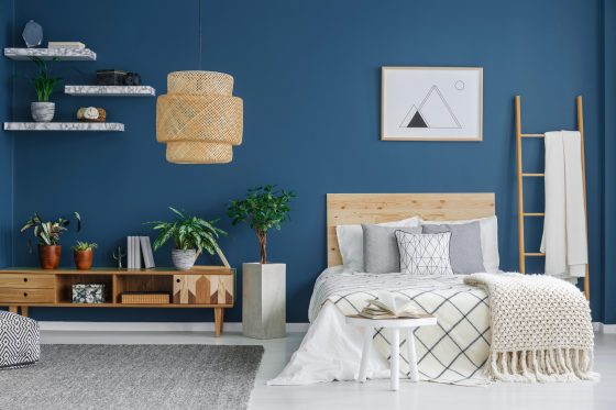 Cozy bedroom interior with a double bed, wooden cabinet, chandelier and blue wall