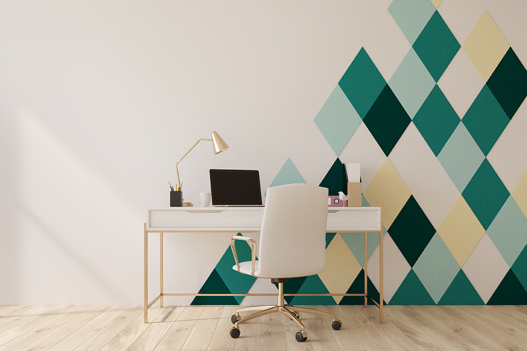 Bright office with a white, green and yellow geometric wall design in the shape of stacked diamonds.